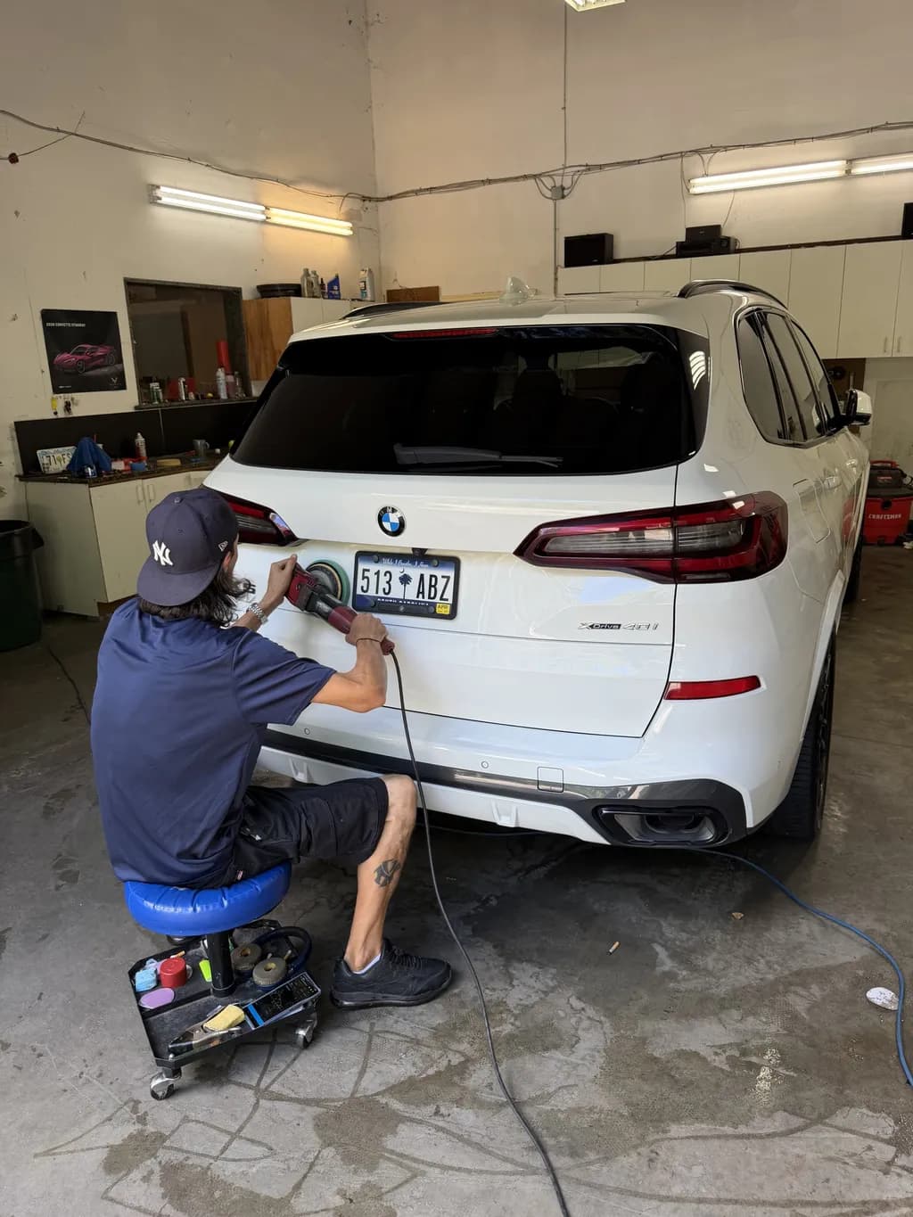An A1 detailer polishing the rear bumper of a white BMW X5.
