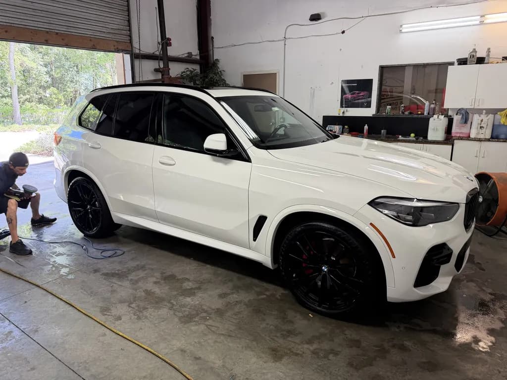 A white BMW X5 being cleaned in the detailing bay.