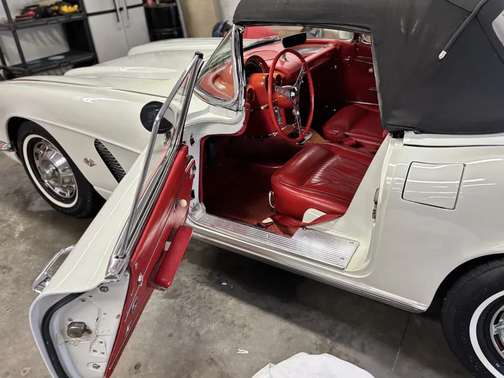 The red interior of a white classic Corvette, door open, after detailing.